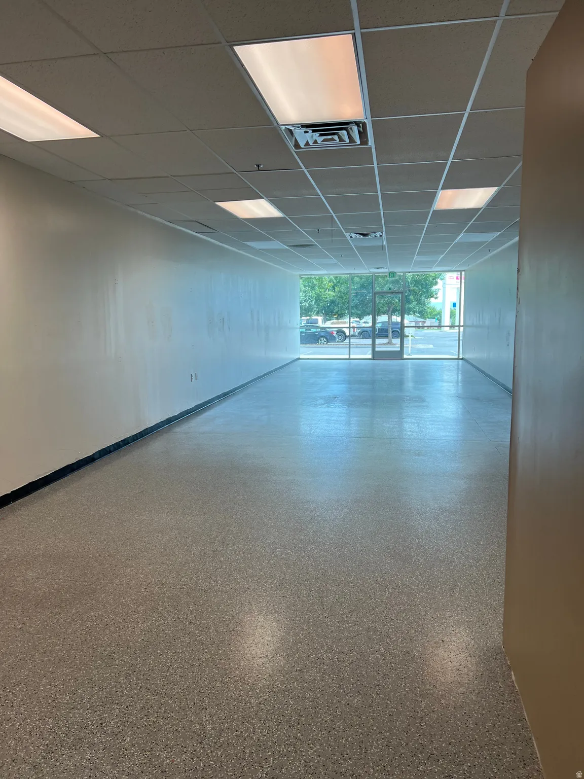 Unfurnished room featuring a paneled ceiling and dark aggregate flooring