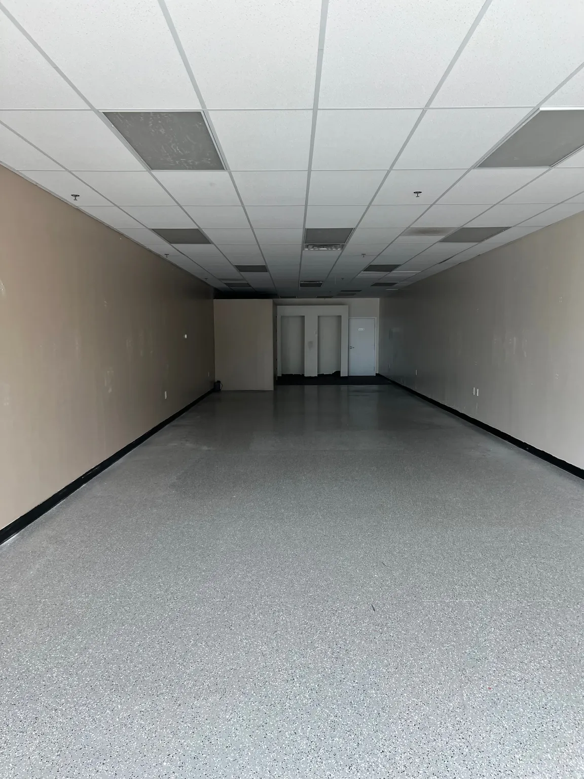 Unfurnished room with speckled floor and a drop ceiling