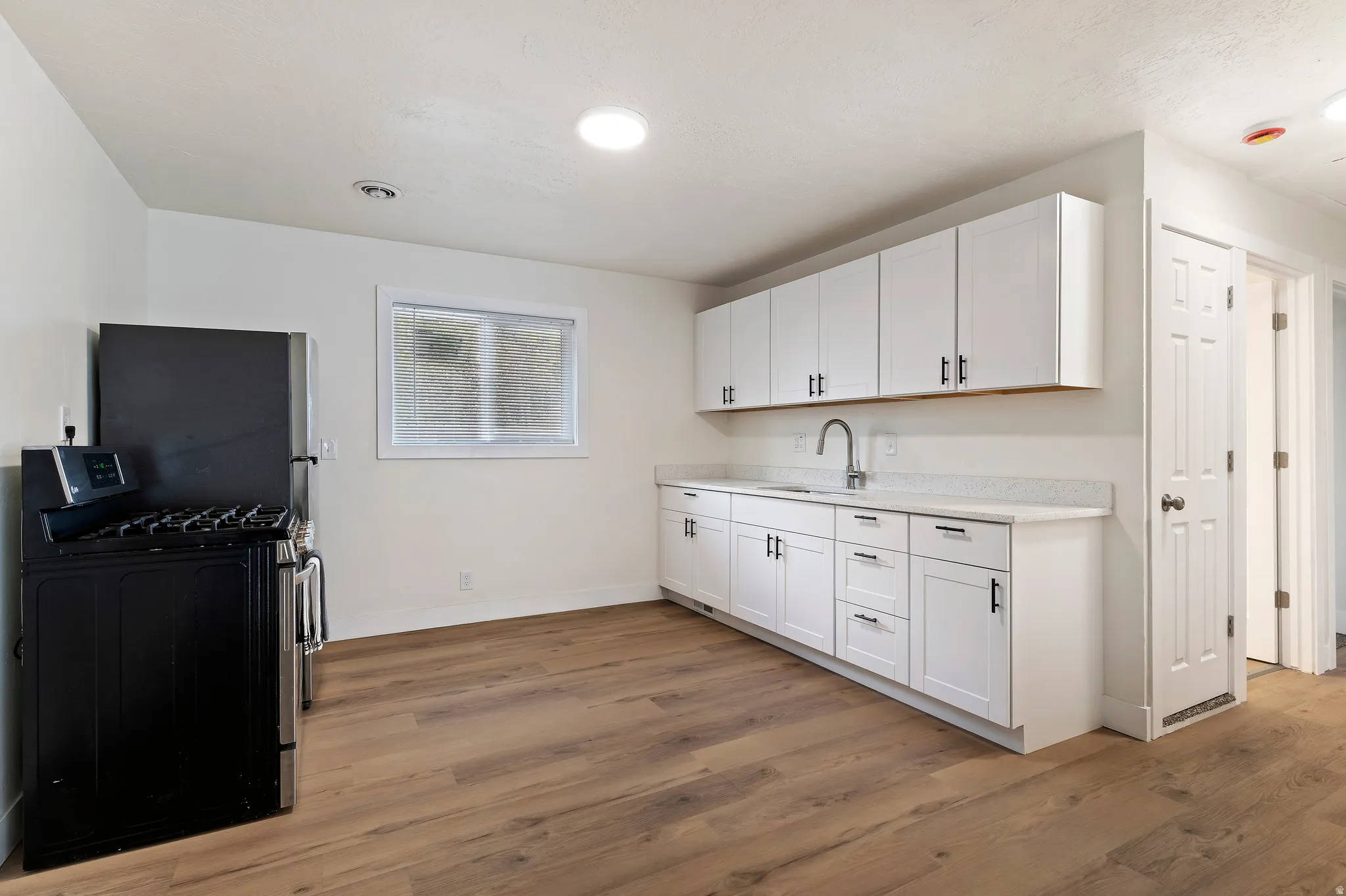Unit 2 Kitchen featuring light countertops, light wood-type flooring, appliances with stainless steel finishes, and white cabinets