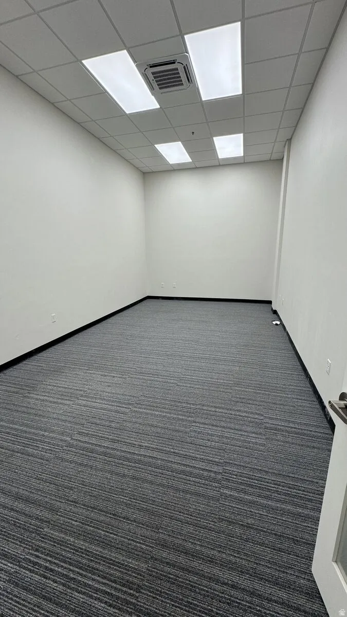 Unfurnished room with dark carpet and a drop ceiling