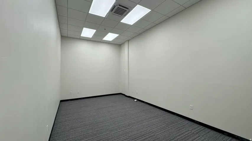Empty room featuring dark carpet and a paneled ceiling