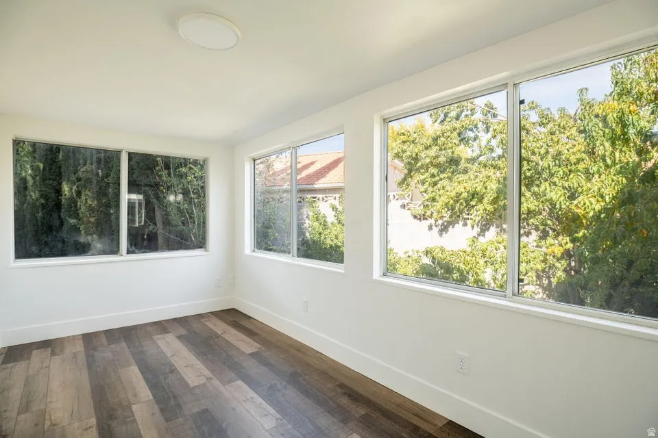 Unfurnished sunroom with hardwood / wood-style flooring and baseboards