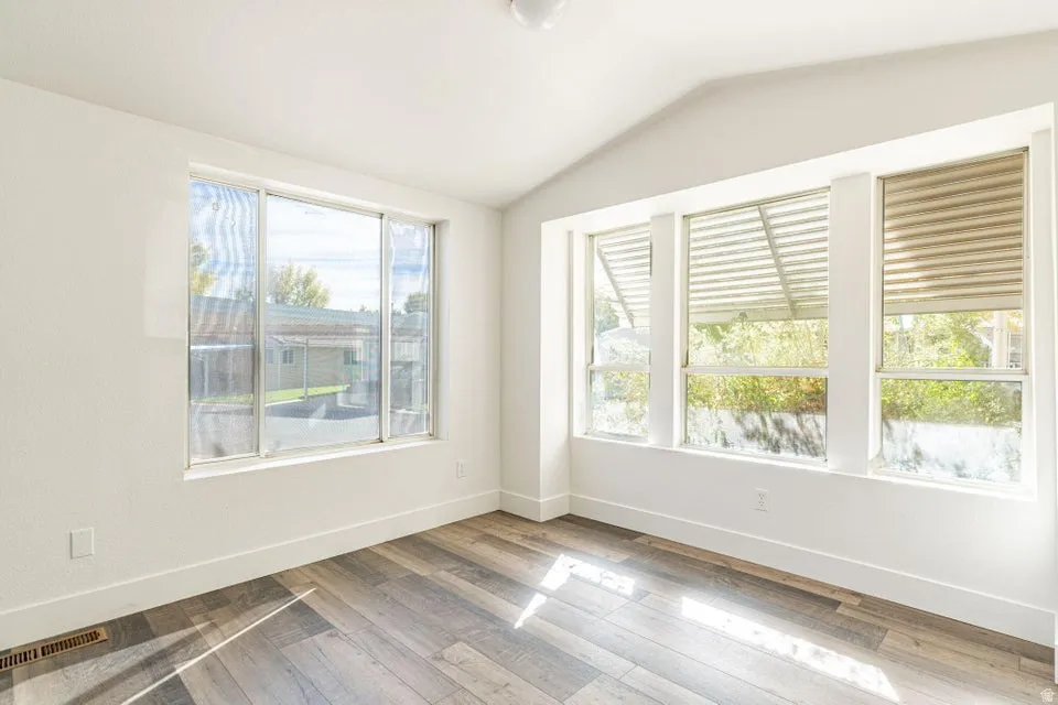 Unfurnished room featuring vaulted ceiling and wood finished floors