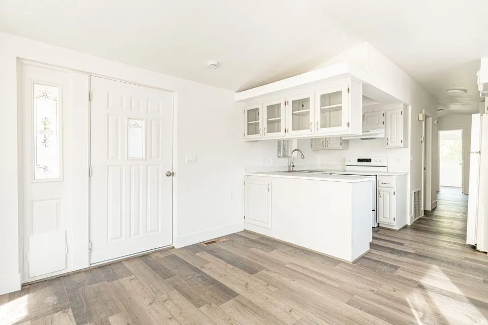 Kitchen with glass insert cabinets, white cabinets, light countertops, and white appliances