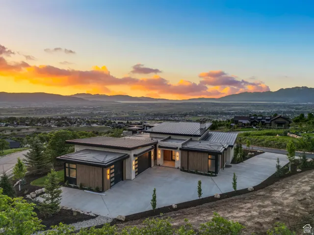 Rear view of example property featuring an attached garage, a metal roof, concrete driveway, and a mountain view