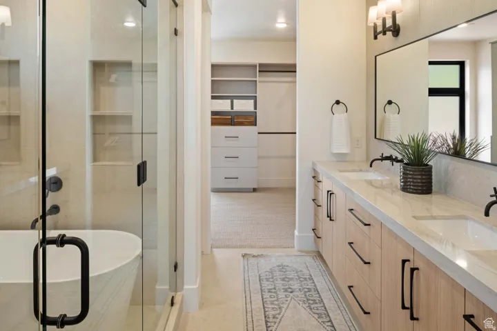 Example of full bathroom featuring a spacious closet, double vanity, and a stall shower