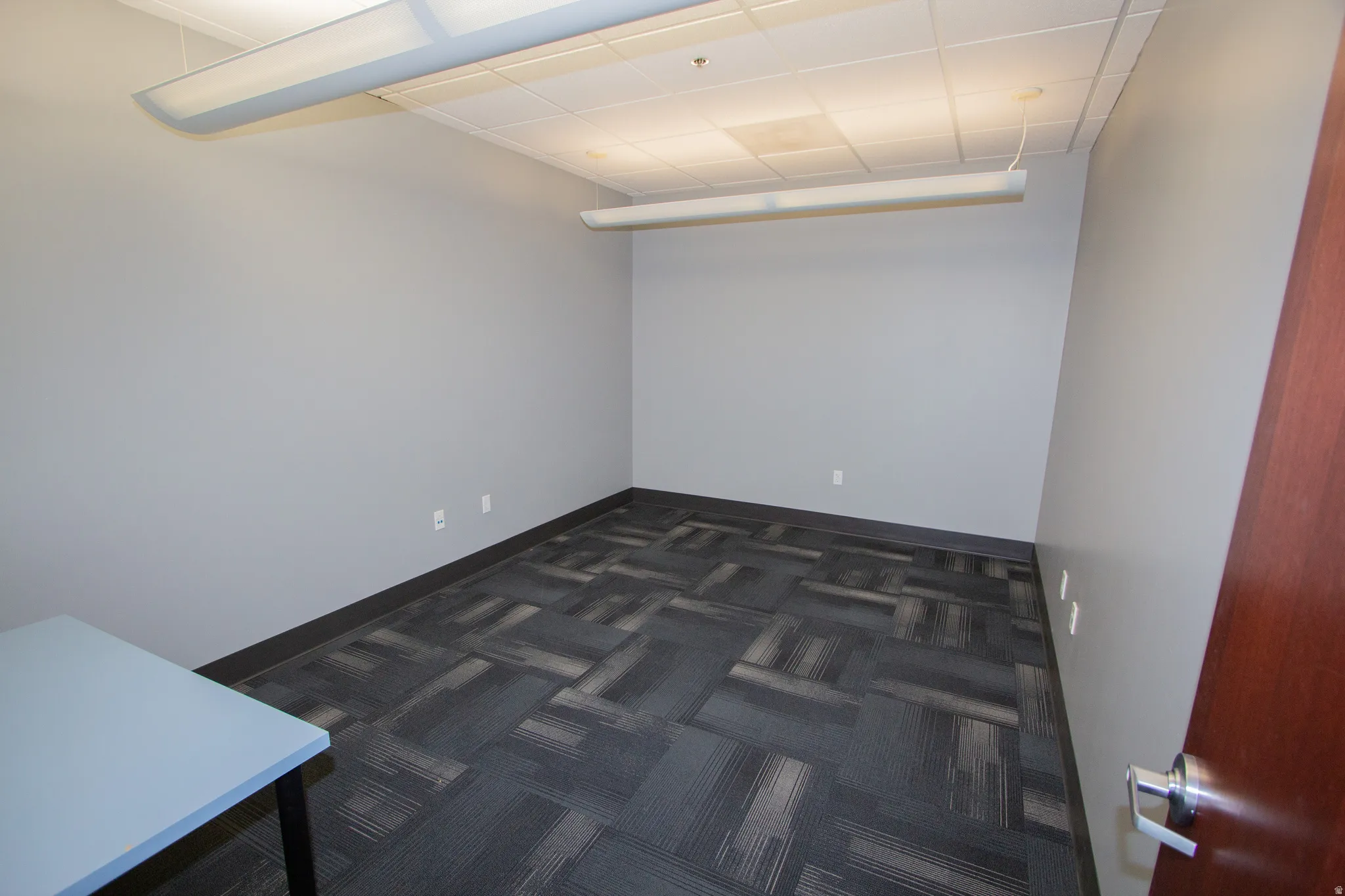 Empty room with dark colored carpet and baseboards