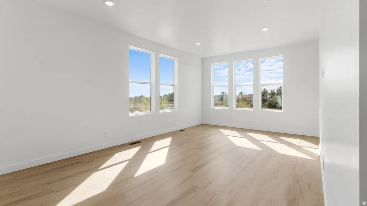 Empty room with light wood-style flooring and recessed lighting