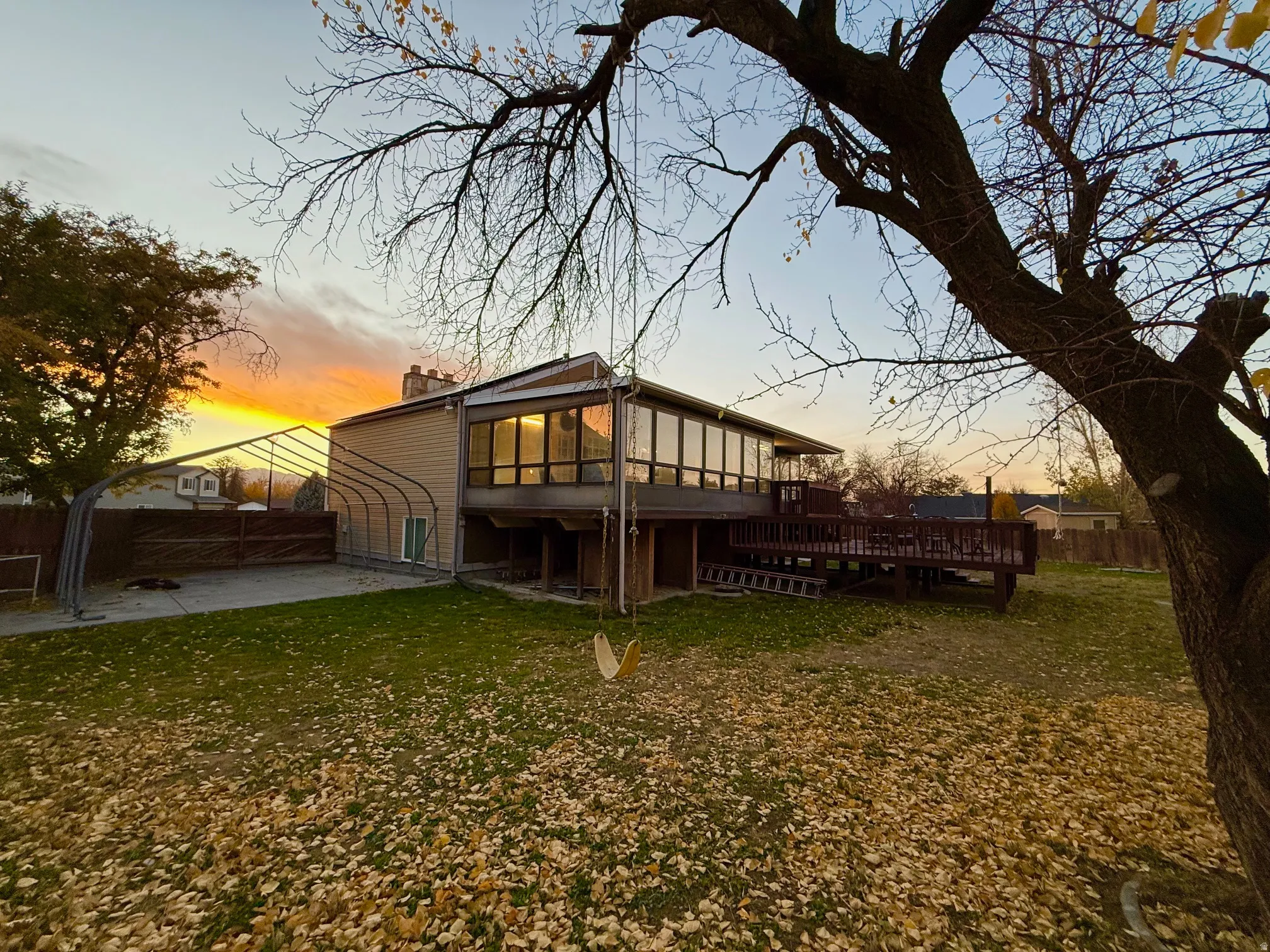 Back of property at dusk with a wooden deck, a chimney, and a patio