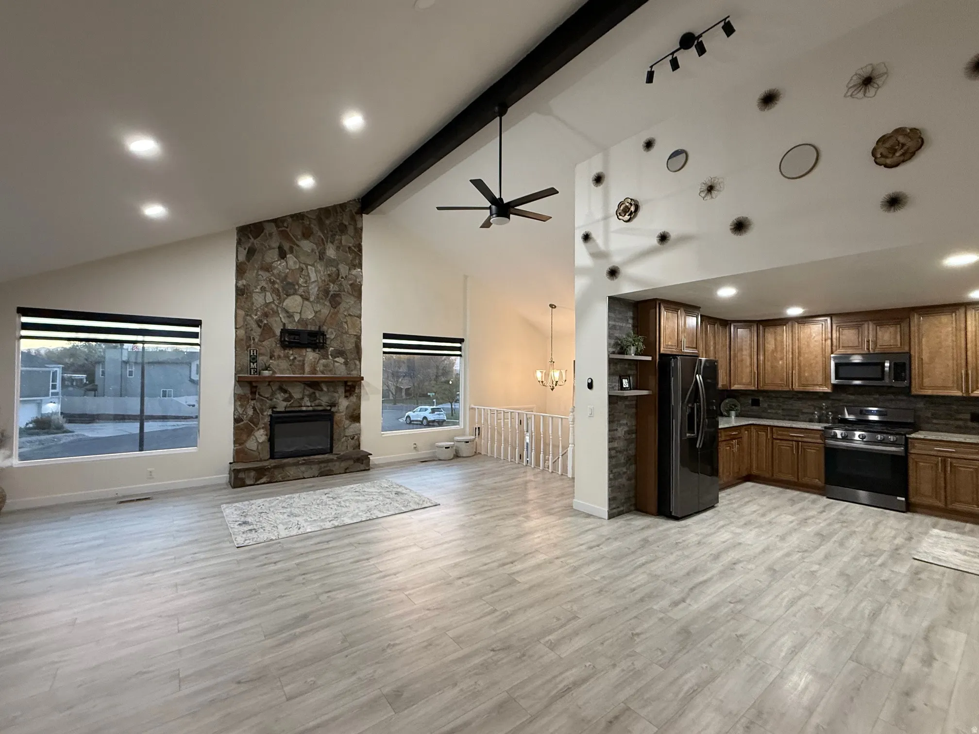 Kitchen featuring open floor plan, stainless steel appliances, beam ceiling, recessed lighting, and high vaulted ceiling