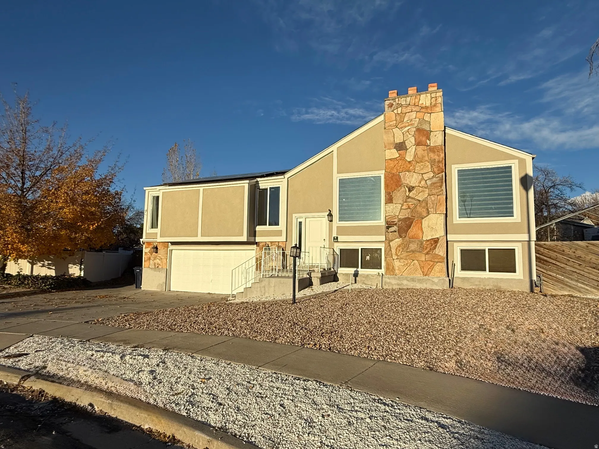View of front facade with stucco siding, concrete driveway, a chimney, and a garage