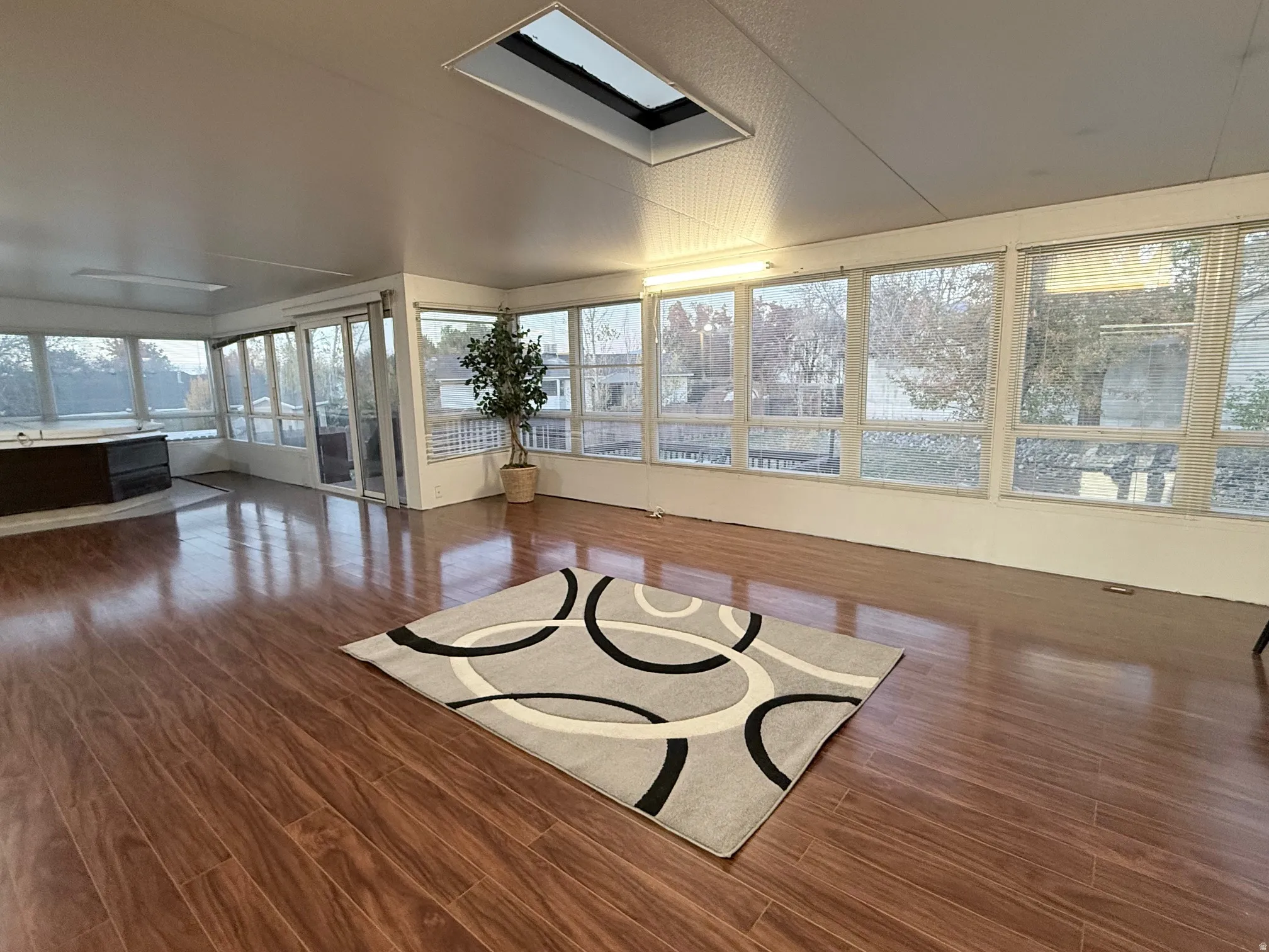 Sunroom / solarium with wood finished floors and a skylight