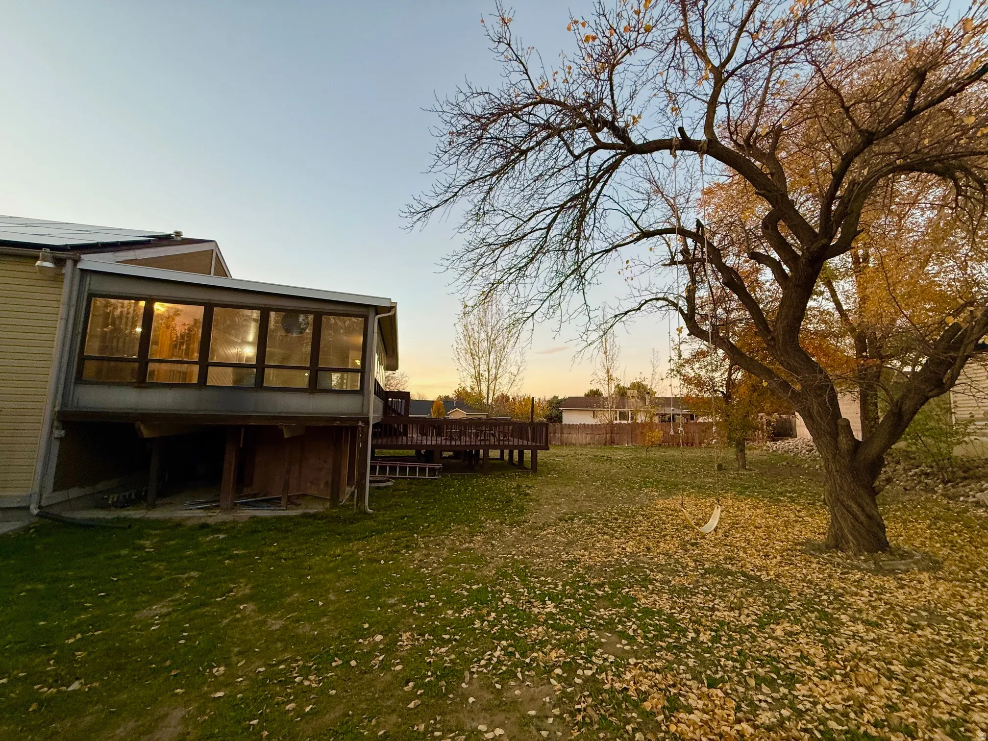 Yard at dusk with a sunroom, a wooden deck, and a yard