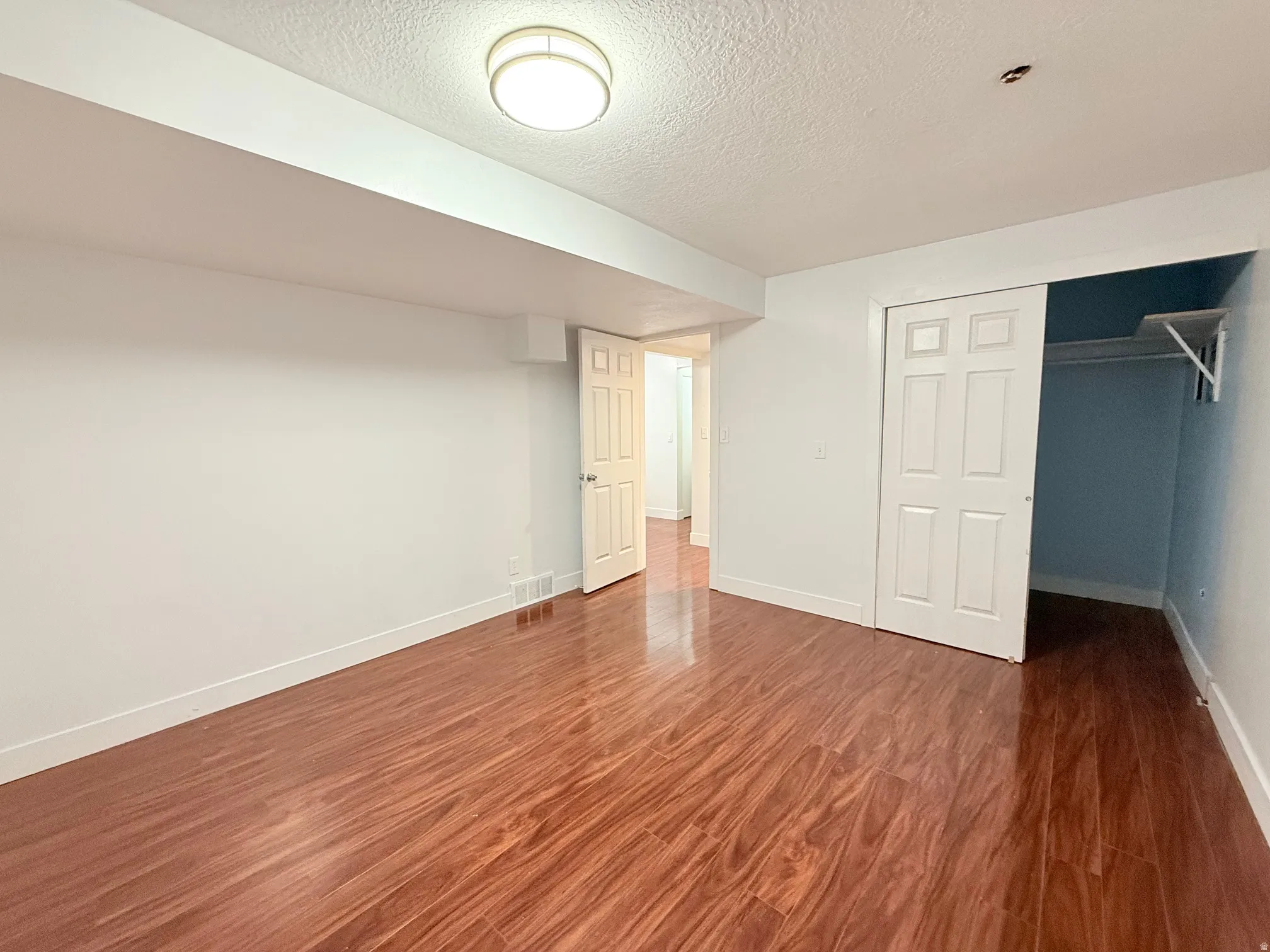 Unfurnished bedroom featuring a textured ceiling, dark wood-type flooring, and a closet