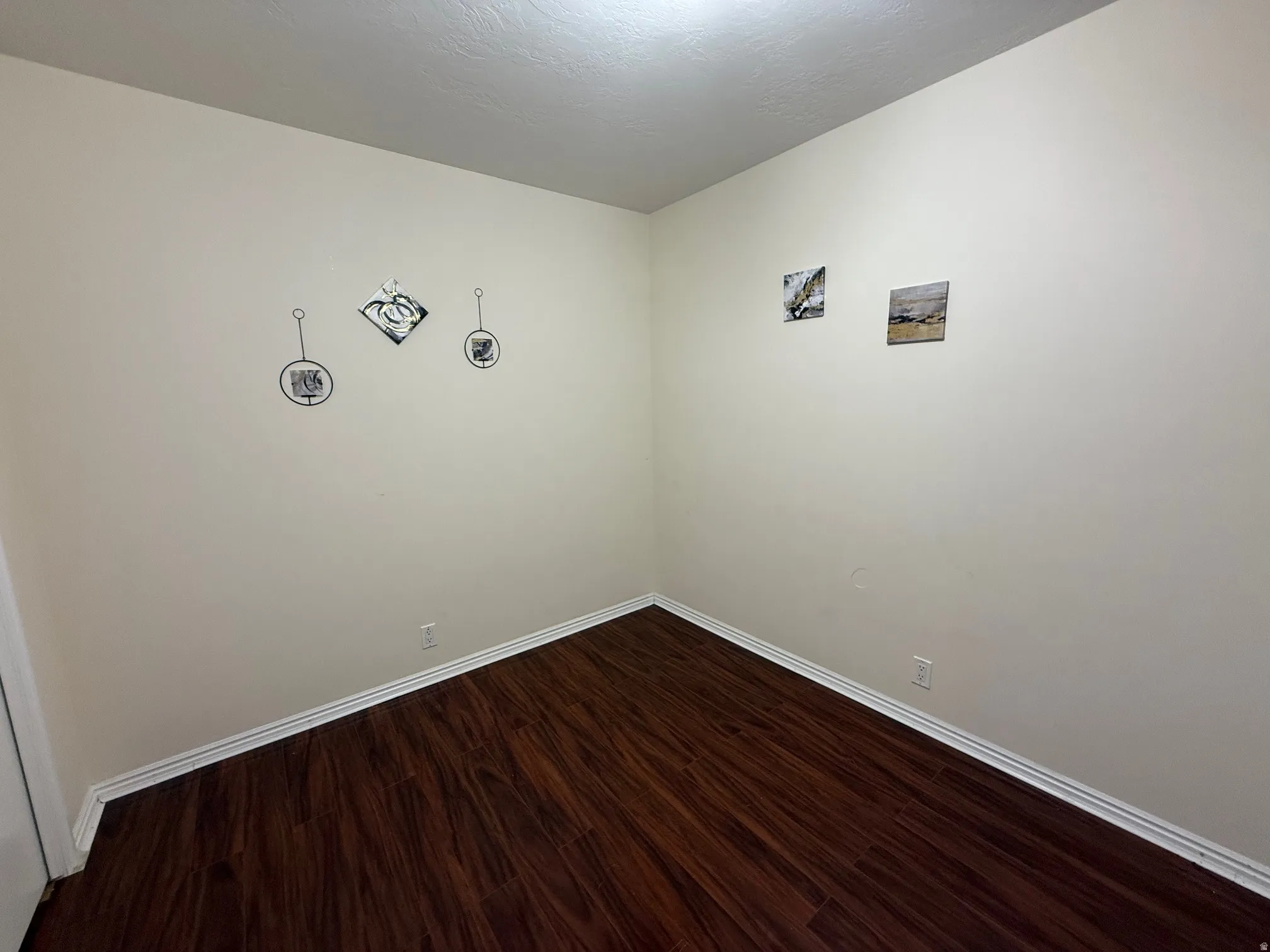 Unfurnished room featuring dark wood-style flooring and baseboards
