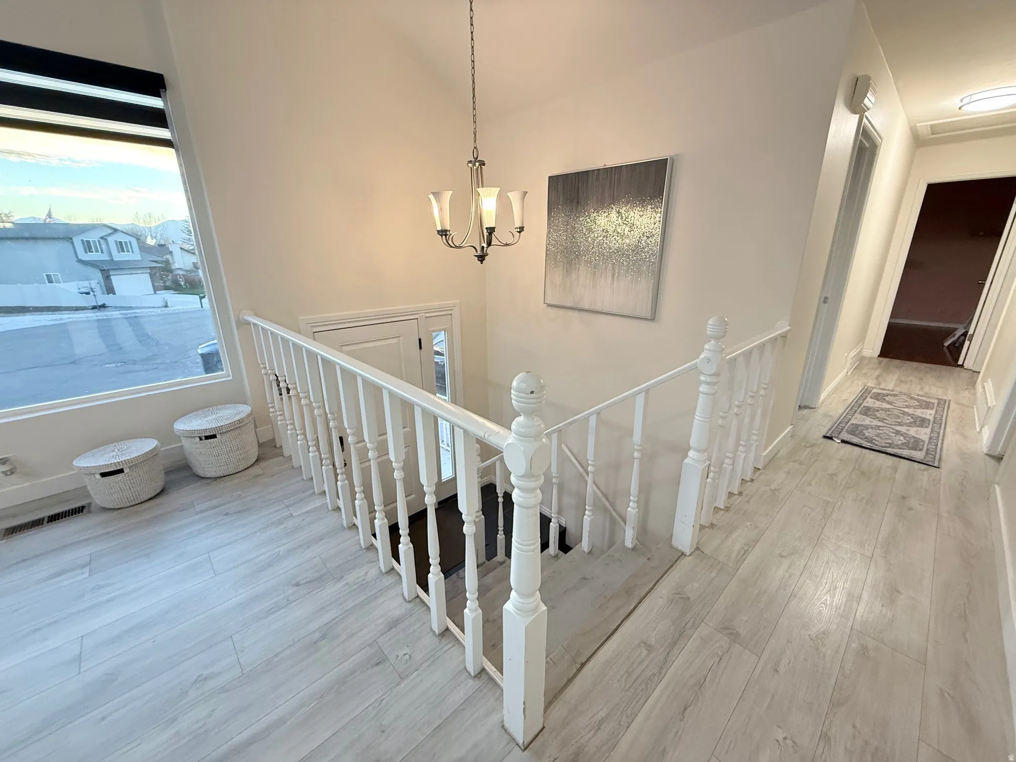 Stairs with wood finished floors and a chandelier