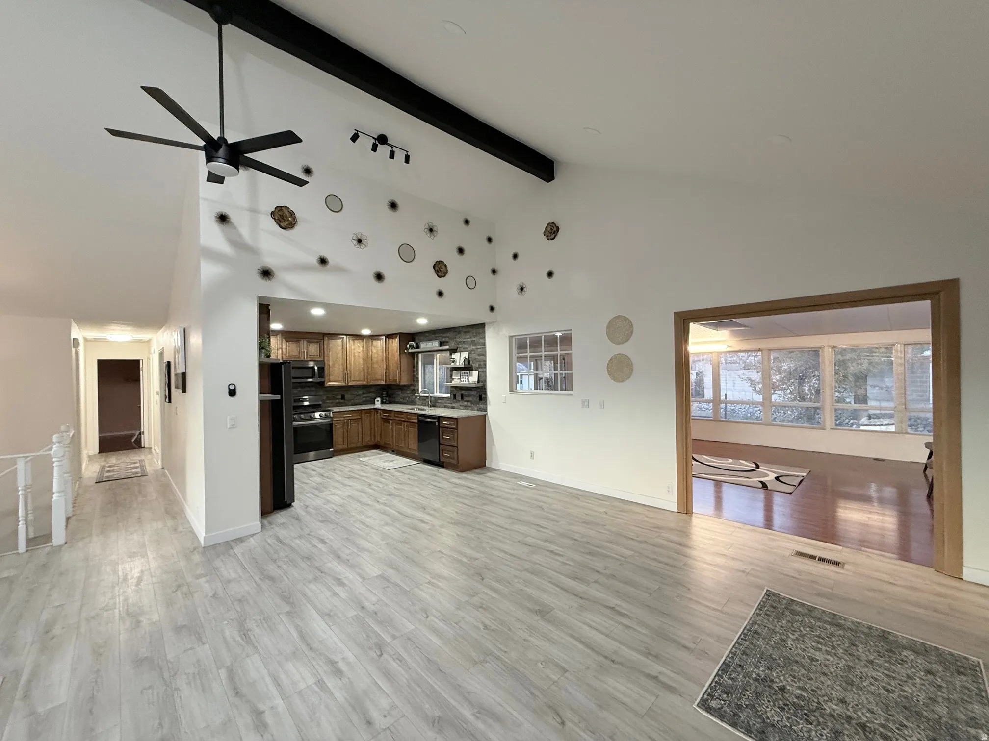 Kitchen featuring open floor plan, ceiling fan, high vaulted ceiling, backsplash, and beamed ceiling