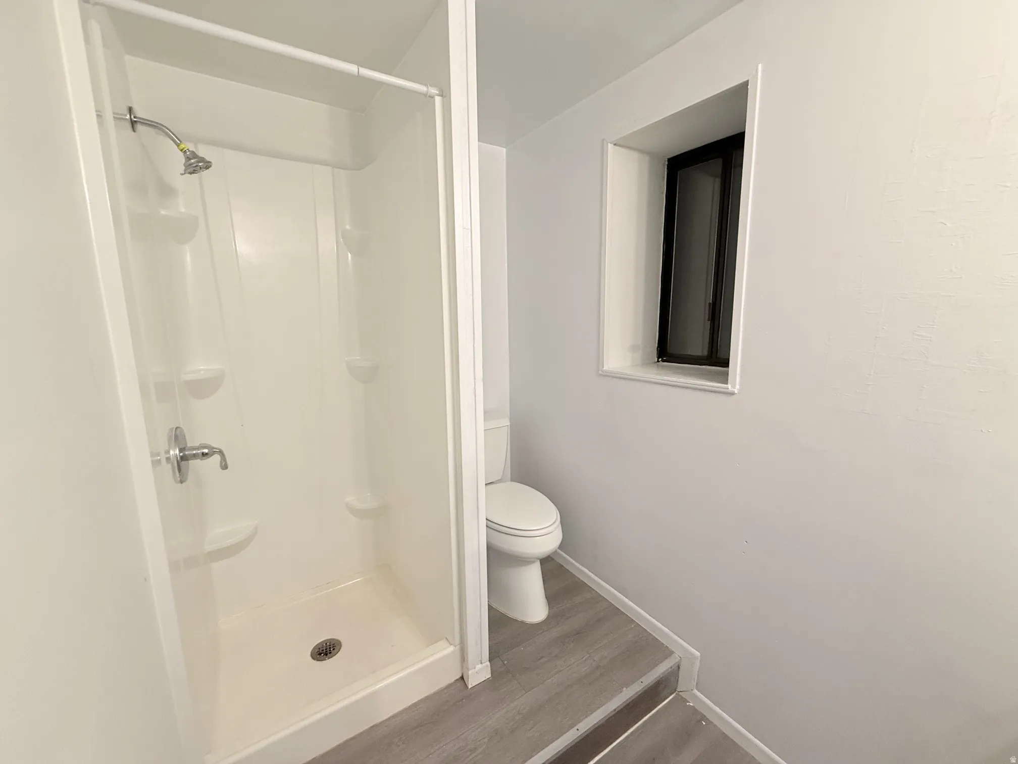 Bathroom featuring a shower stall and dark wood-style flooring