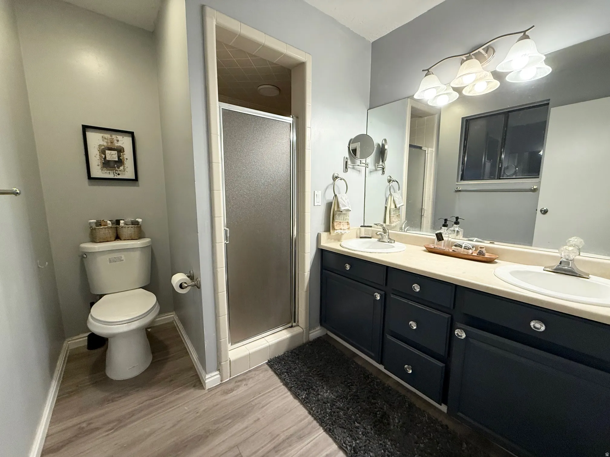 Bathroom with a stall shower, double vanity, and light wood-style flooring