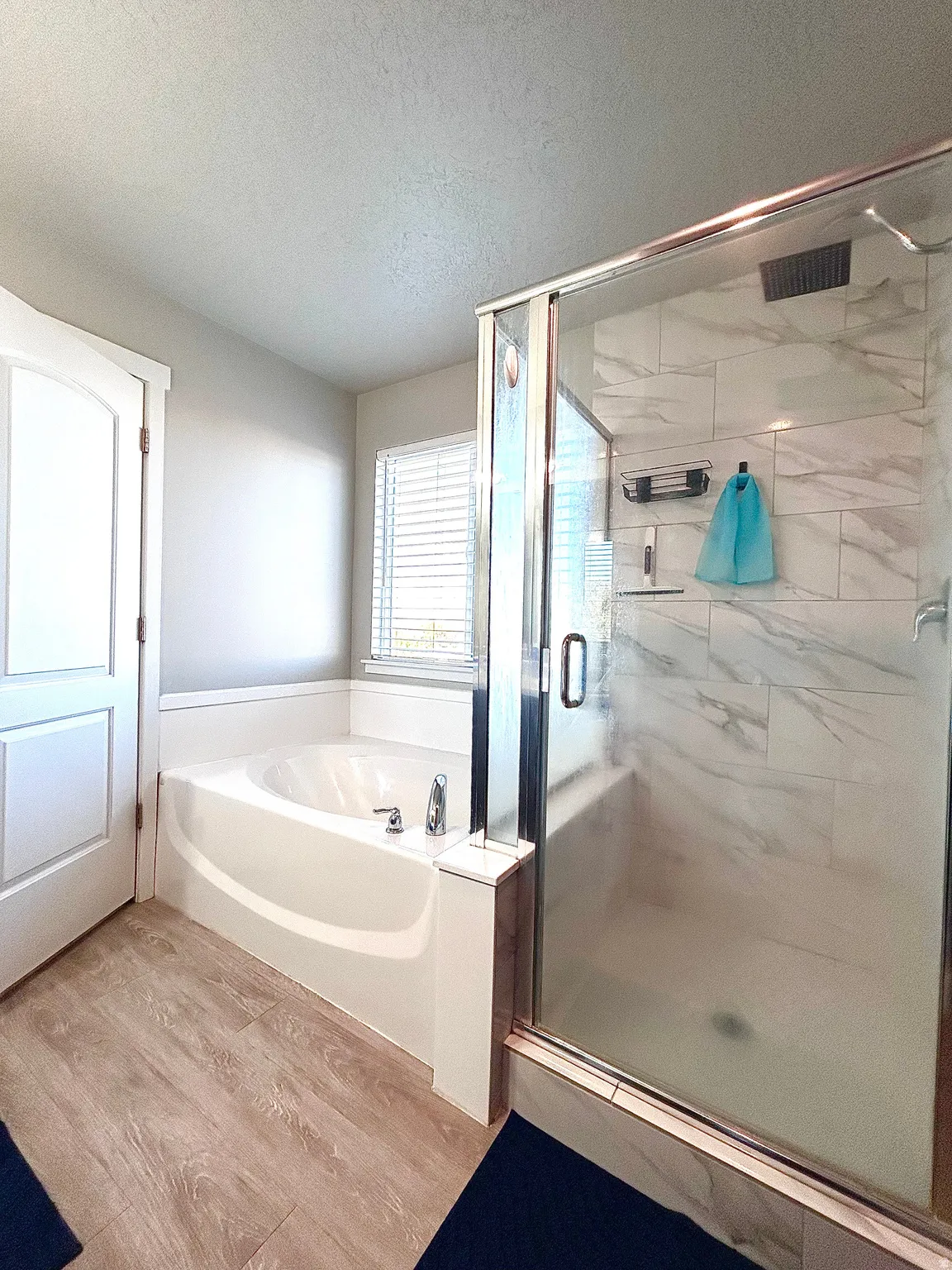 Full bath featuring a textured ceiling, light wood-style floors, a shower stall, and a bath