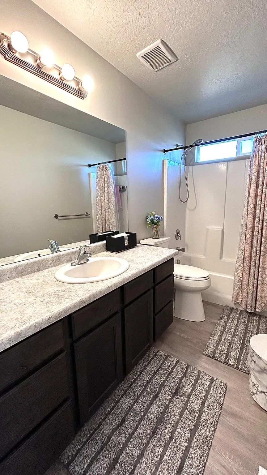 Bathroom featuring dark wood finished floors, vanity, shower / bath combination with curtain, and a textured ceiling