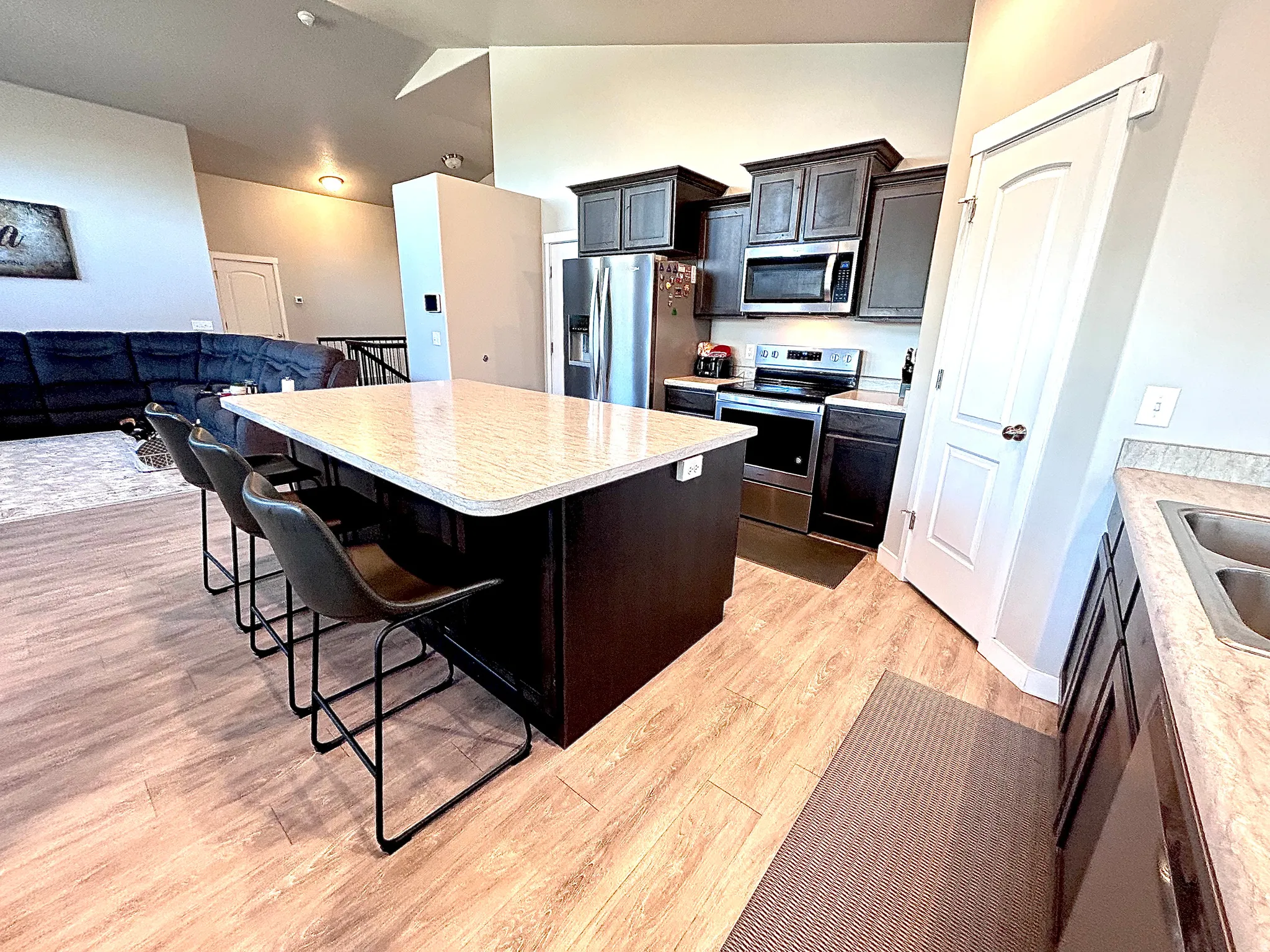 Kitchen with stainless steel appliances, a kitchen bar, open floor plan, light countertops, and a center island