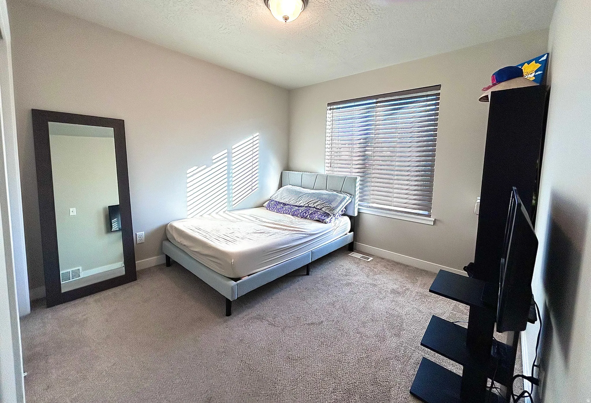 Bedroom with light colored carpet and a textured ceiling