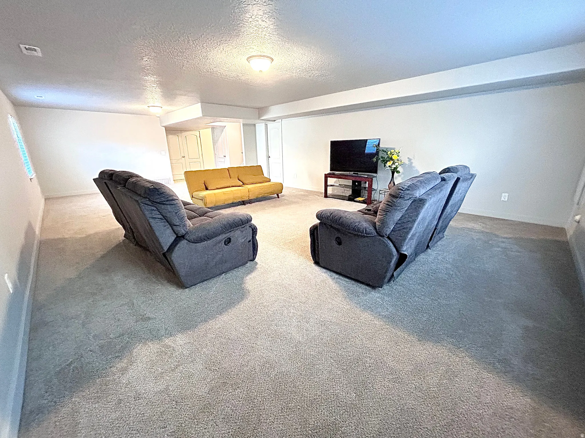 Carpeted living area featuring a textured ceiling and baseboards