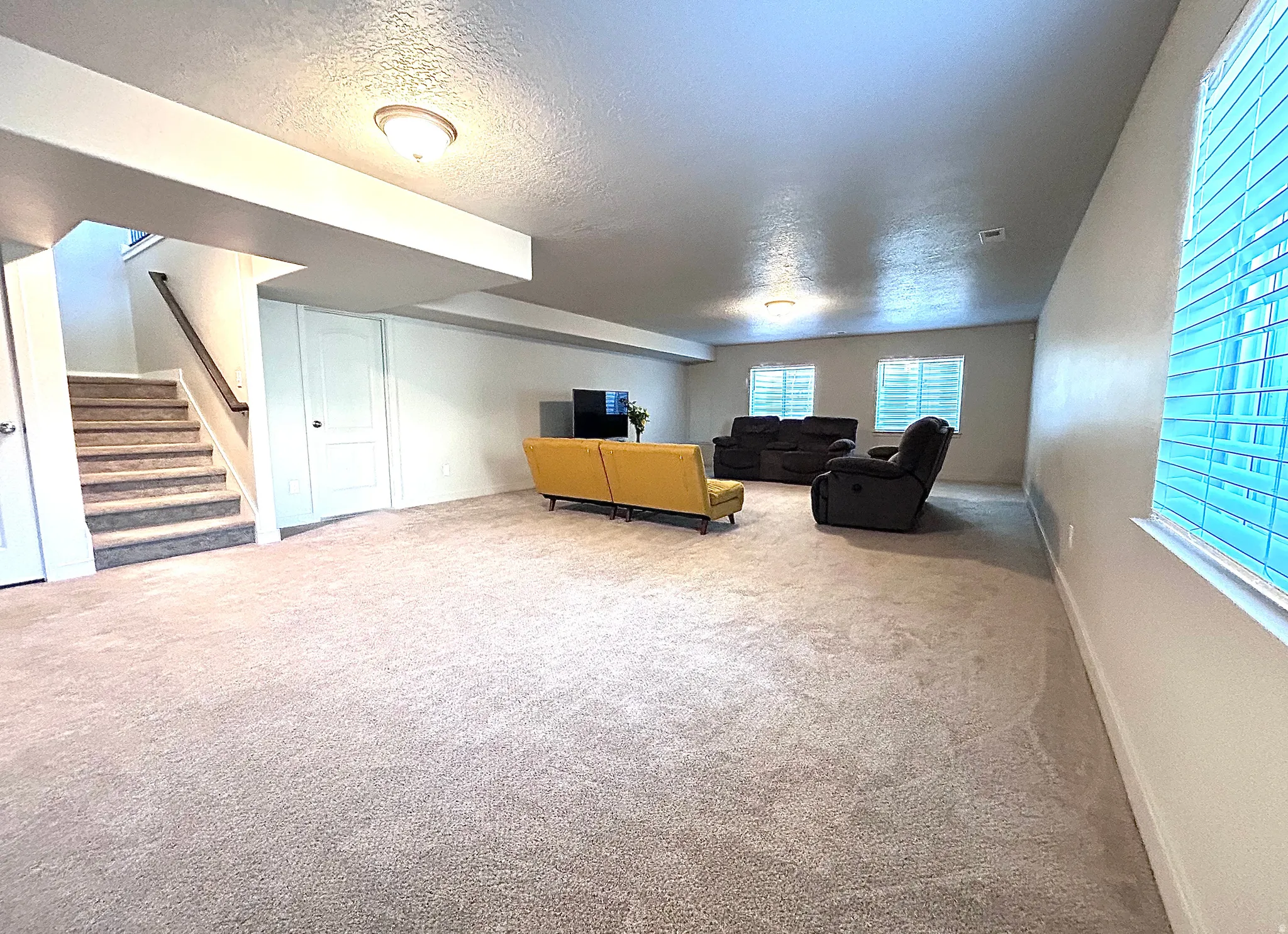 Carpeted living room featuring a textured ceiling and stairway