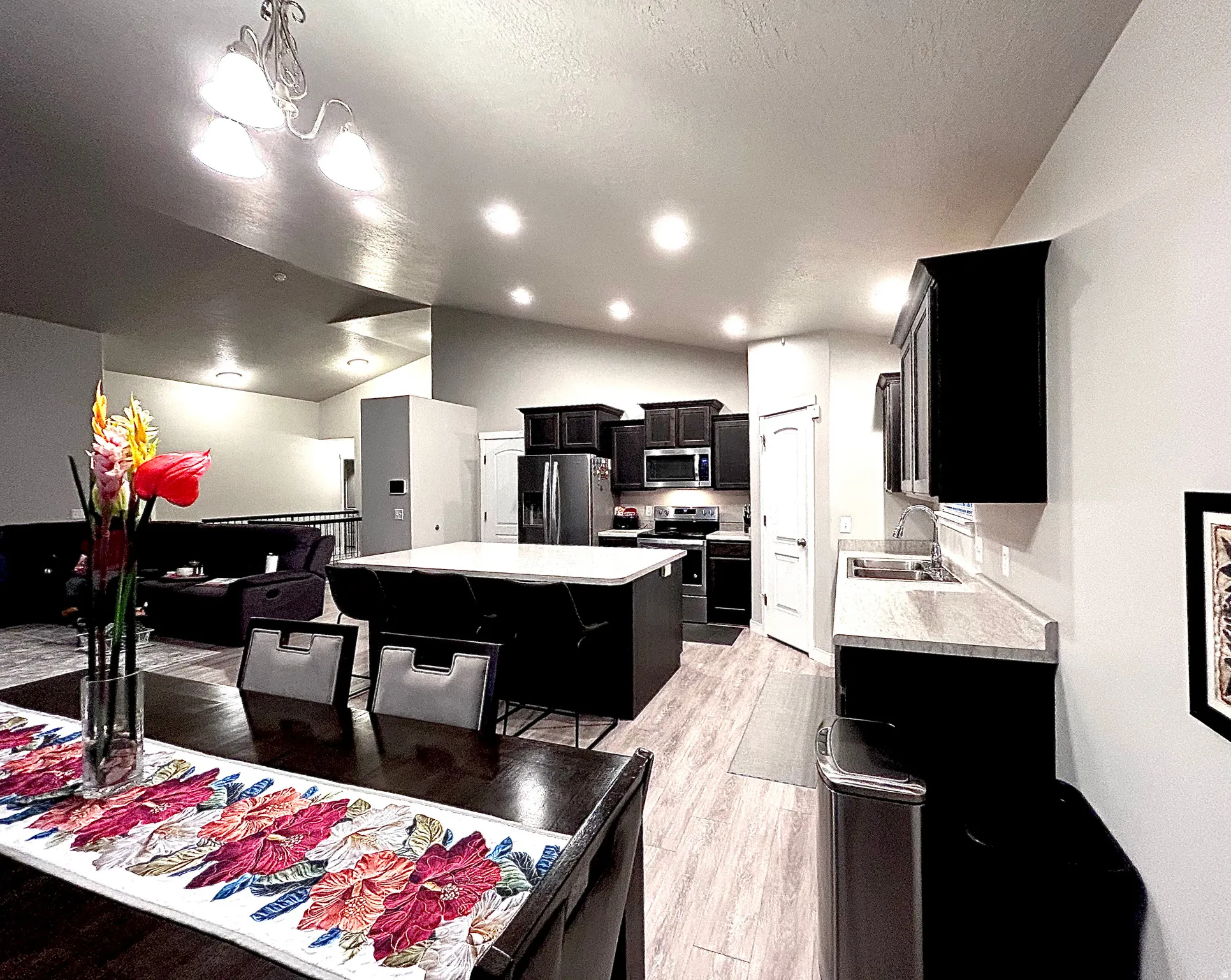 Kitchen with dark cabinetry, lofted ceiling, light countertops, a center island, and light wood-style flooring