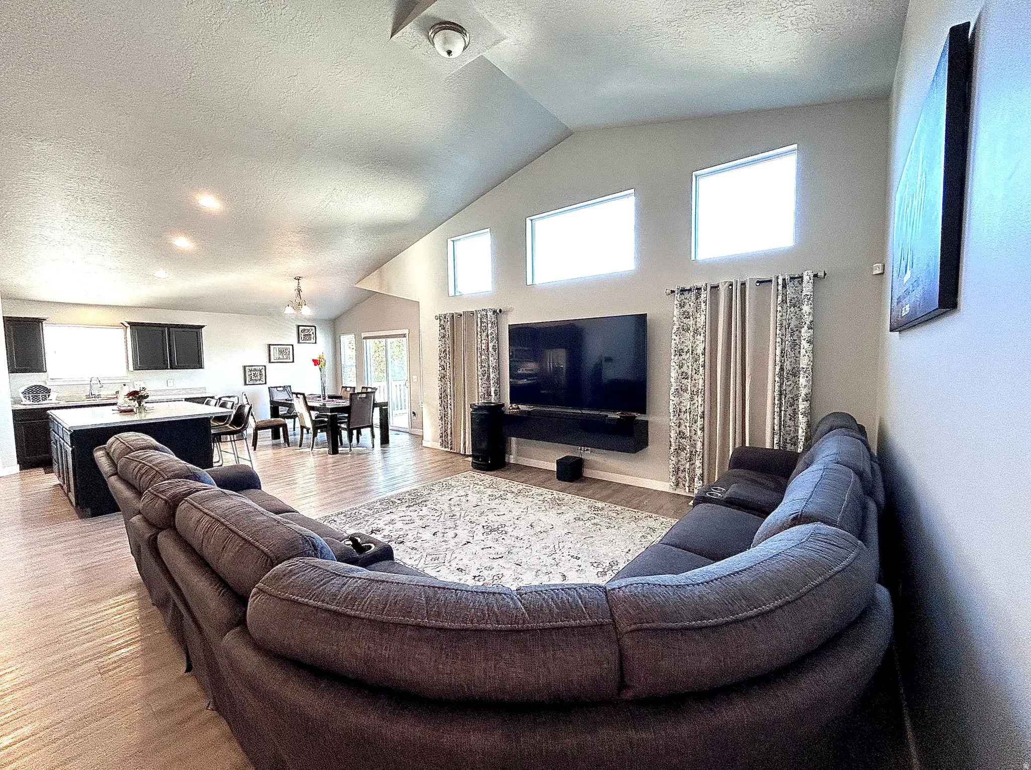 Living area featuring a textured ceiling, high vaulted ceiling, and light wood finished floors