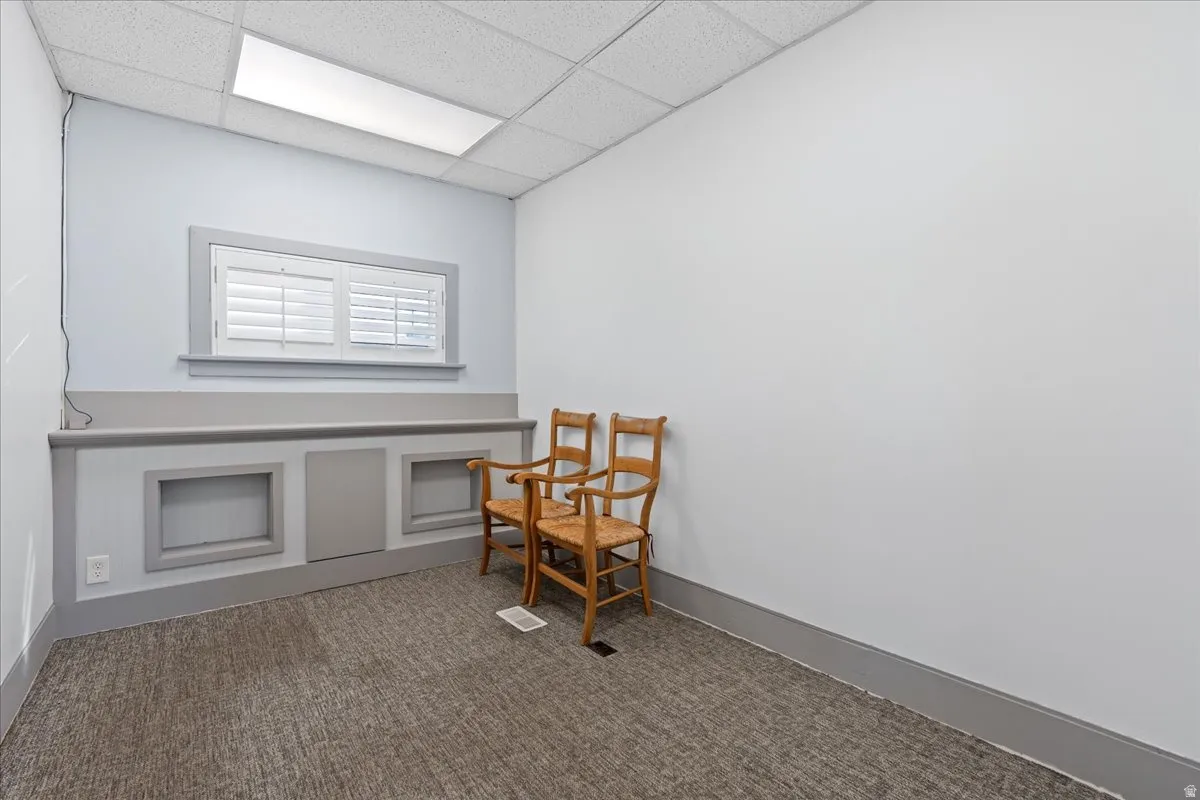 Living area featuring dark colored carpet and a paneled ceiling