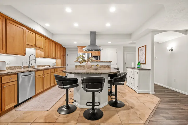 Spacious open kitchen with under-cabinet lighting, granite countertops, a pantry, and a large central island