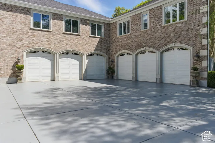 View of front of property featuring brick siding, concrete driveway, and a garage