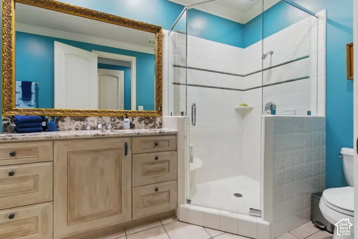 Full bathroom with vanity, light tile patterned flooring, crown molding, and a stall shower