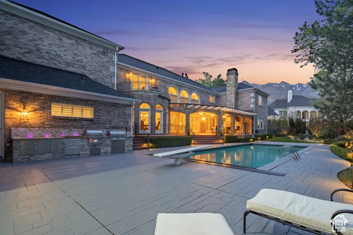 Swimming pool featuring exterior kitchen, a diving board, a patio, and a pergola