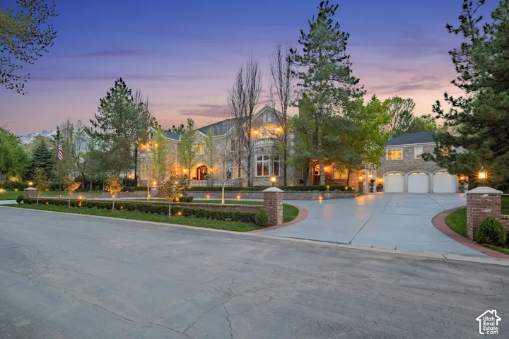 View of front facade with curved driveway, stone siding, and a garage