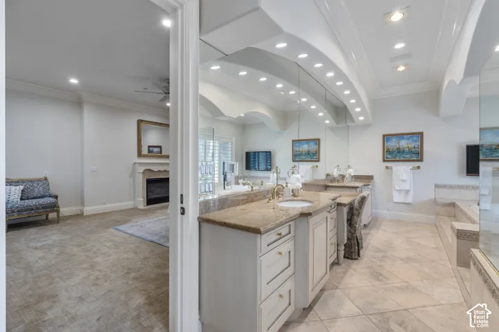 Kitchen with open floor plan, a fireplace, ornamental molding, light stone counters, and recessed lighting