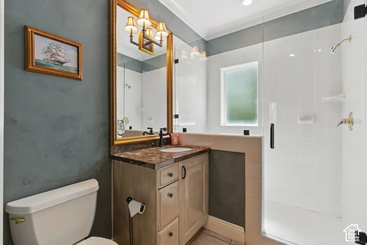 Bathroom with crown molding, vanity, a shower stall, and light tile patterned floors