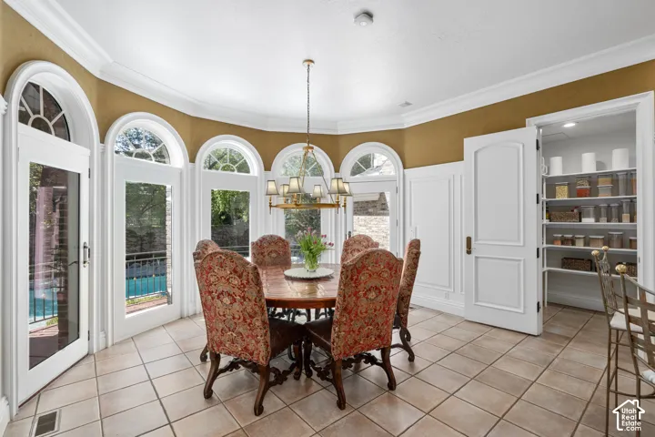 Dining area with light tile patterned floors, a chandelier, and ornamental molding