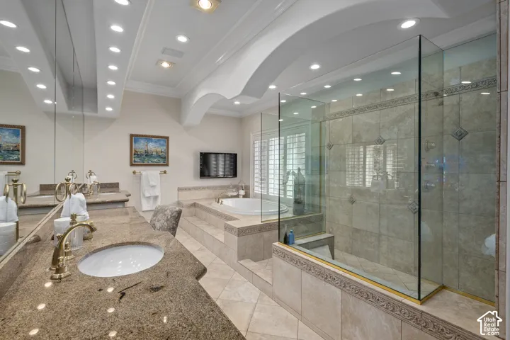 Full bathroom with vanity, crown molding, a garden tub, a shower stall, and light tile patterned floors