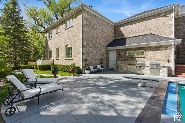 Back of house featuring an outdoor kitchen, a patio, and brick siding