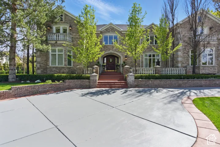 French country style house featuring french doors, a balcony, and brick siding