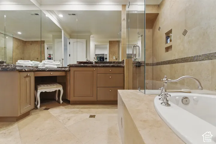 Bathroom featuring vanity, a bath, crown molding, a stall shower, and tile walls