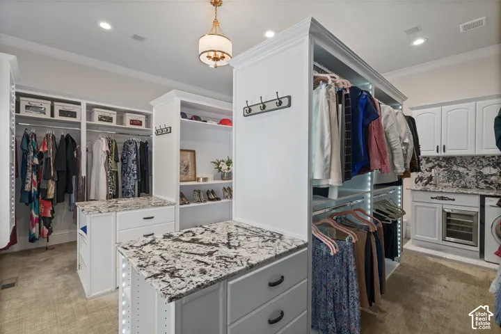 Spacious closet featuring light colored carpet, washer / clothes dryer, and beverage cooler