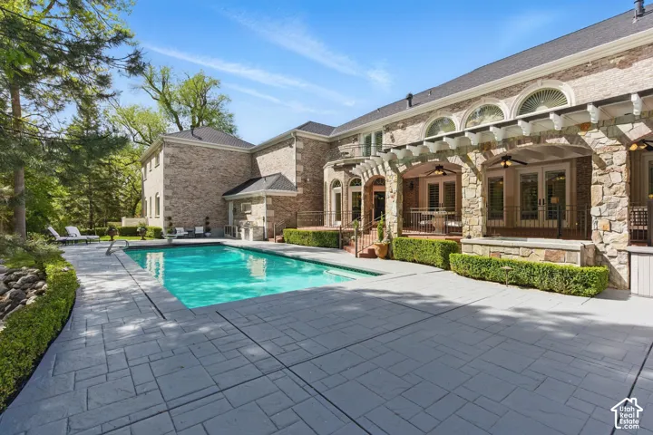 View of swimming pool with ceiling fan and a patio