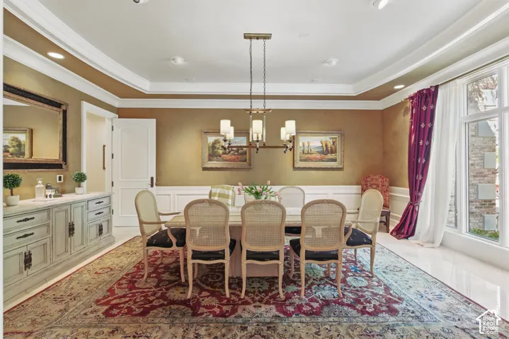 Dining room with a raised ceiling, a decorative wall, a wainscoted wall, recessed lighting, and a chandelier