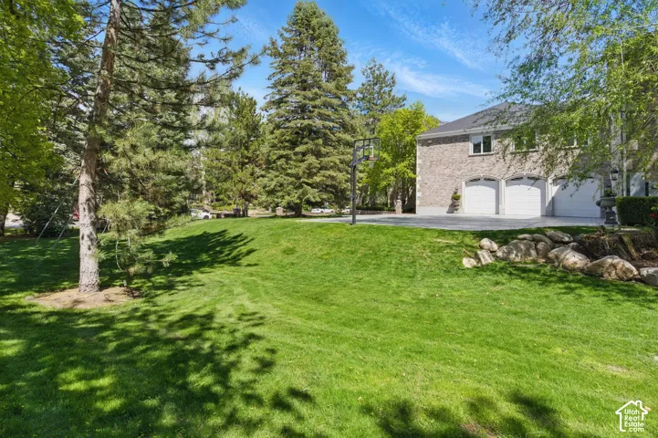 View of grassy yard featuring asphalt driveway and a garage
