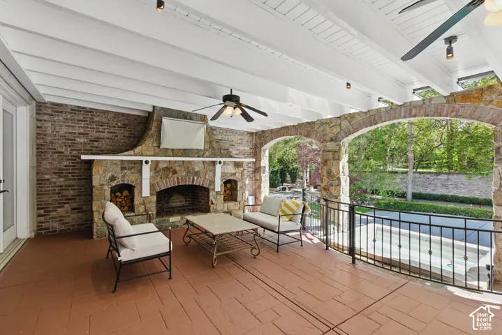 View of patio / terrace with a ceiling fan, an outdoor living space with a fireplace, and an outdoor pool