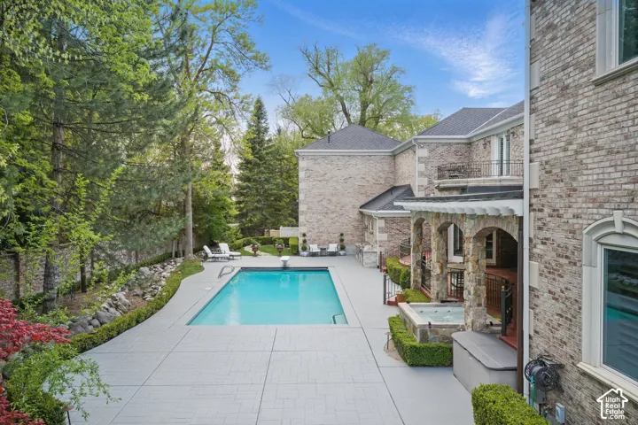 Swimming pool with a jacuzzi, a patio area, a balcony, and a diving board